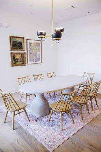 A white table surrounded by chairs and a rug in a room.